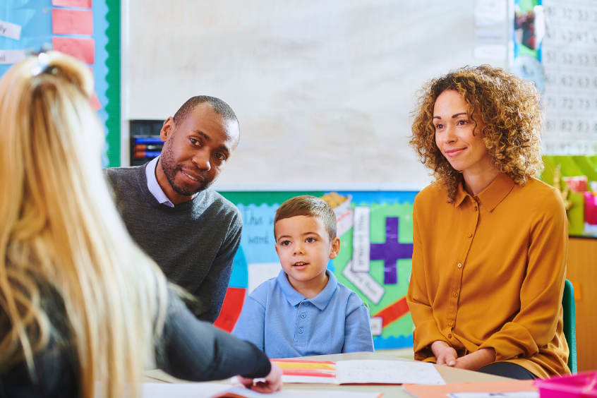 Parents and their child meeting with a teacher in a preschool classroom