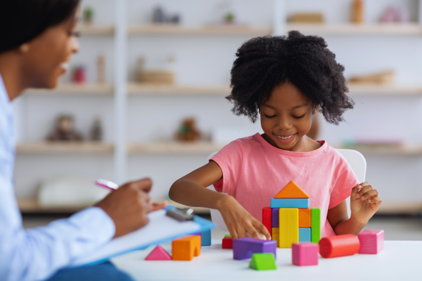 Therapist working with a young child on a learning activity in a classroom