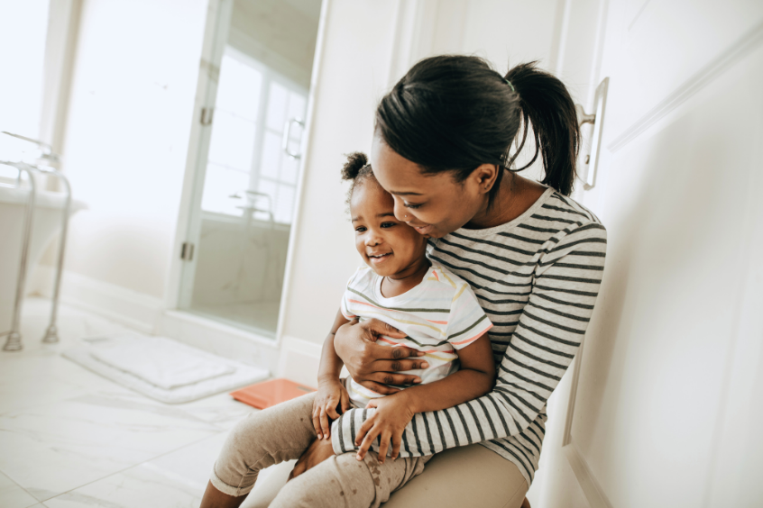 Mother helping her young child in the bathroom during potty training