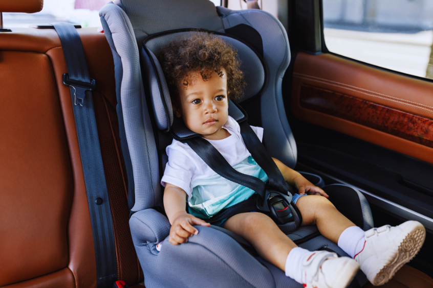 Young child safely secured in a car seat inside a vehicle.