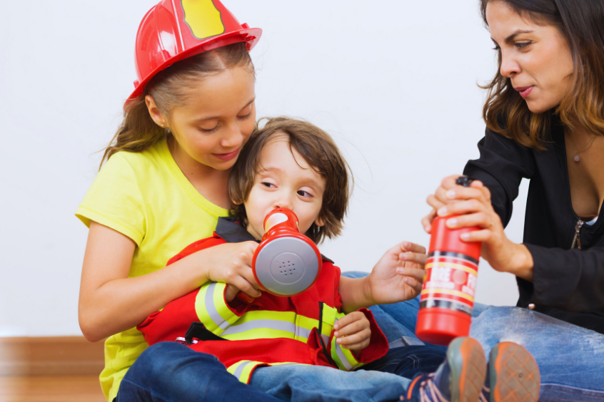 Children practicing fire safety with an adult using a toy fire extinguisher